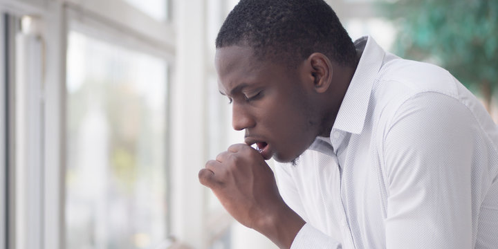 Sick African man coughing; Portrait of ill black man cough due to cold, flu, allergy, polluted air, fine dust, tuberculosis; air pollution, lung cancer, emphysema concept; African man model