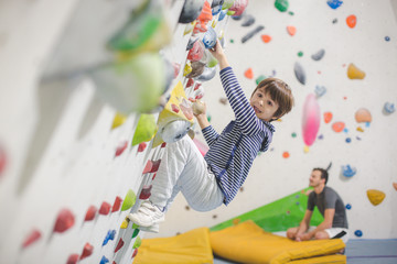 Sweet little preschool boy, climbing wall indoors