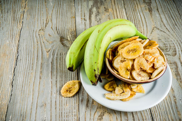 Dried bananas plantains with fresh bananas, wooden background copy space
