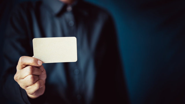 businessman handing name card to introduce himself, dark background space for web page design or cover