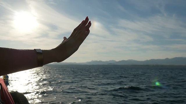 Woman`s hand on a ship`s starboard  at splendid sunset in Egypt in slo-mo 