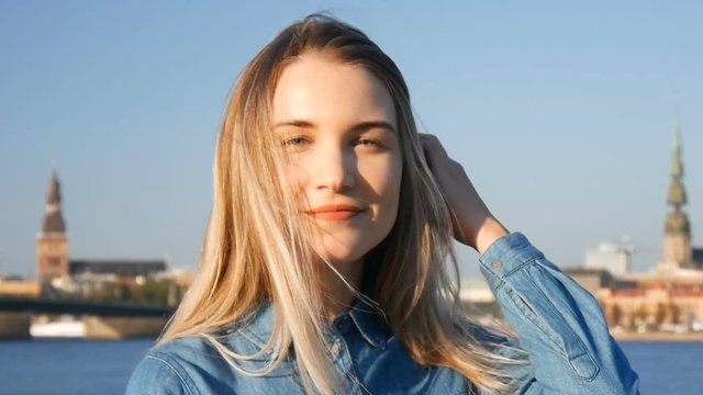 Portrait of a beautiful blond lady in summer sunset with Riga city panorama on the background