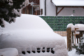 snow-covered vehicle on a barbeque in winter with a thick blanket of snow