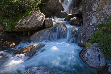 Water filled with mineral salts, flows impetuously among the stones of a stream on the slopes of Mount Rosa in Piedmont, Italy