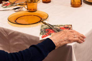 Old woman sitting and holding hand on table