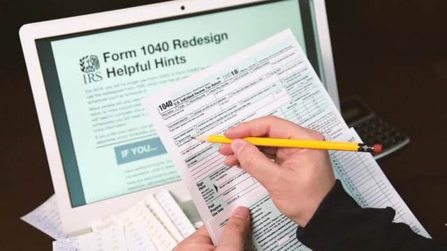 1040 Redesign Helpful Hints on a Laptop Monitor, Man's hand reviewing form 1040.
