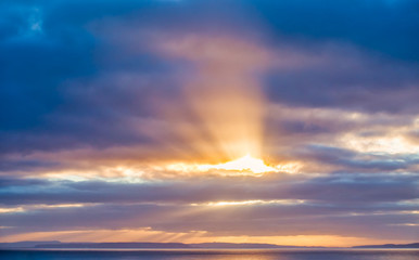 Sun Rays Bursting through Dark Blue Clouds onto the Sea