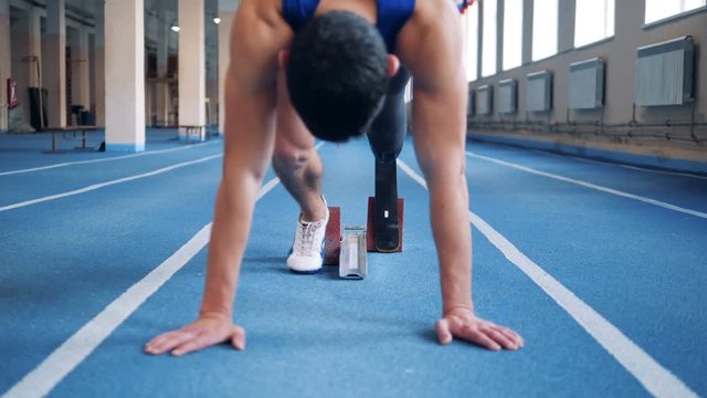 Sprinter with prosthesis stands on a start, close up.