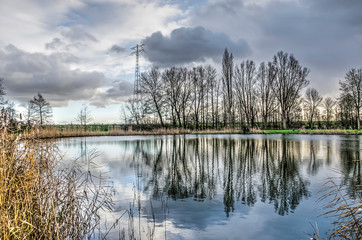 Fototapeta na wymiar Dramatic cloudy sky reflecting in a little lake, or :wiel