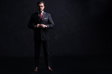 Full length portrait of a fashion male model over black background. Looking at camera.