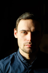 Business portrait of a handsome young man in a dark blue shirt.