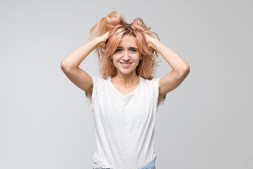 Fototapeta premium Studio portrait of cute woman in white t-shirt looking at camera and attractive smile, holds hands on the head/good-looking, cheerful lady, satisfaction, people, beauty and lifestyle concept.