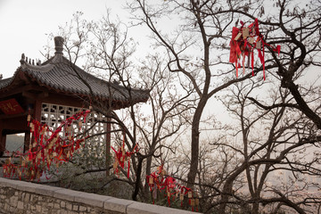 trees with red ribbons and pavilion in the Xingguochan Temple on The Thousand Buddha Mountain autumn evening, Jinan, China
