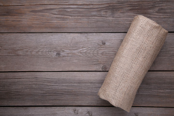 Rolled up sackcloth on grey wooden background