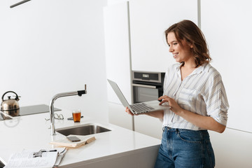 Happy young businesswoman standing at the kitchen