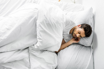 top view of handsome young man sleeping in bed in the morning