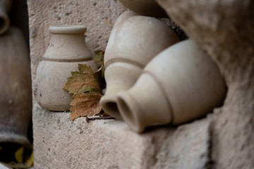 Antique ancient stone utensils vase on stone wall and grape leaf