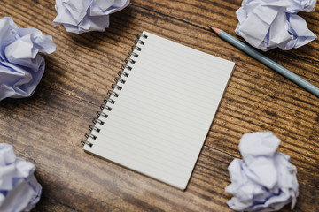 minimalist desk setting flatlay with opened ruled notepad and pencil surrounded by scrunched paper...