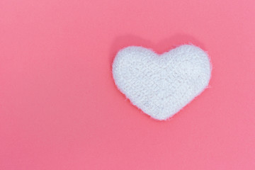 Fluffy white heart on pink background. Soft toy in shape of heart. Love concept. Minimalism.