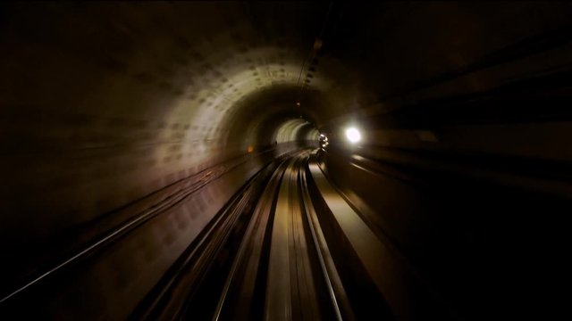 View of subway tunnel as seen from the rear window of moving train. Fast underground train departs from modern subway station.