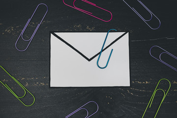 funny metaphor of inbox with email envelop and attachment clip on real-life desk