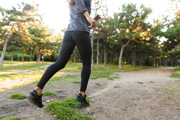 Skinny african american woman 20s wearing black tracksuit, running through green park