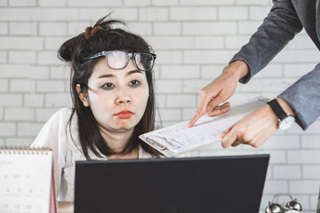 sleepless Asian woman tired and sleepy sitting at desk lazy to work with boss complaining in...