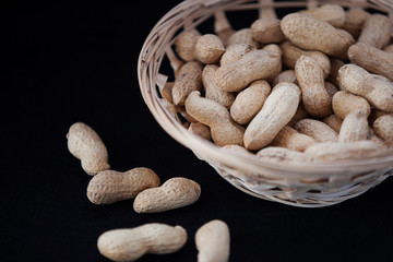 peanuts in a wicker basket on a black background