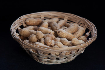 peanuts in a wicker basket on a black background