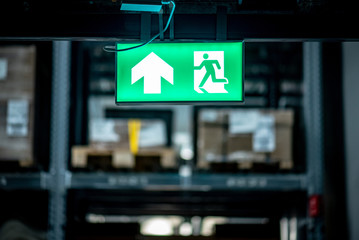 Green emergency exit sign or fire exit sign showing the way to escape with arrow symbol.