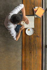 High angle view of young man enjoy free day, reading book, drinking coffee