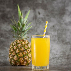 glass of pineapple juice with fresh fruits on grey bacground