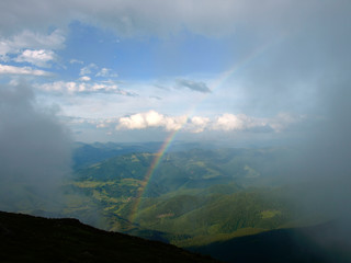 Picturesque landscape of Carpathian mountains with rainbow over them.  Heaven kitchen prepares rainy whether in summer in mountains. Eastern Carpathians, Ukraine