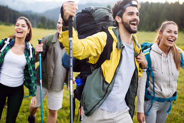 travel, tourism, hike, gesture and people concept - group of smiling friends with backpacks