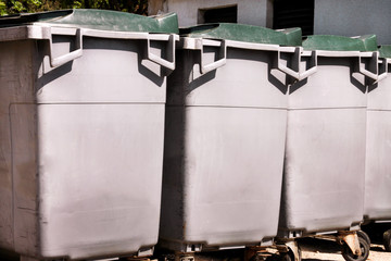 Large garbage containers, trash dumpsters and bins standing in row. Orderly stowed garbage cans ready for separate garbage collection. Environmentally friendly trash containers, recycle bins, tanks.