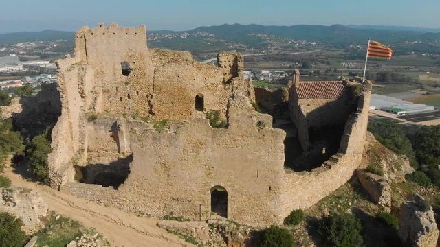 Beautiful landscape of the Palafolls Castle ruins on a sunny day with the Catalonia flag fluttering. Catalonia Spain. Aerial view travelling orbit