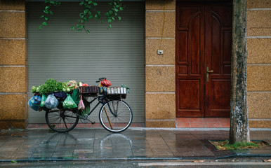 Hanoi city old town. Fruit vendor bicycle. Vietnam at rainy day