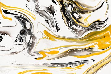 Mixture of acrylic paints. Modern artwork. Yellow and black mixed acrylic paints. Liquid marble texture. Applicable for design packaging, labels, business cards, and interactive web backgrounds.