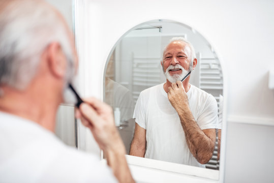 Senior Man Brushing His Beard.