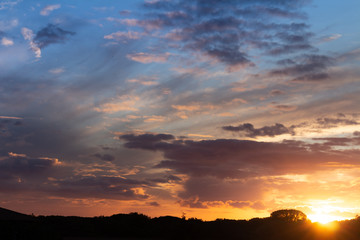 Dawn in the field. Clouds dyed in warm colors during the sunrise.