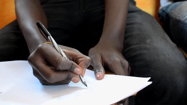 Close-up of hand of young man writing in a seminar in Kibera, Nairobi, Kenya 2