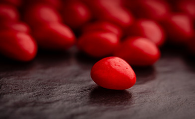 Close up on a red cinnamon heart shaped candy on dark slate