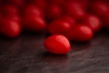Close up on a red cinnamon heart shaped candy on dark slate