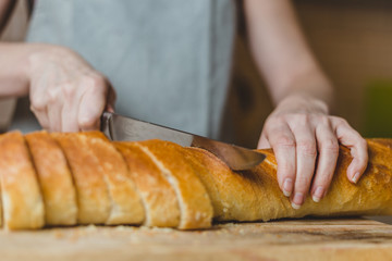 Closeup of housewife preparing snack - tapas and sandwiches - home cooking - step 2 cut baguette