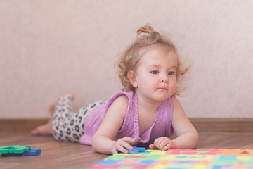 Little girl playing with puzzle on floor