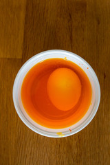 Eier in einem Plastikbecher, um sich für Ostern orange färben zu lassen