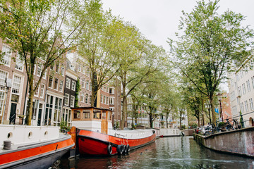 Fototapeta na wymiar Amsterdam, Netherlands September 5, 2017: Canal in Amsterdam, barge, historic tenements and green trees
