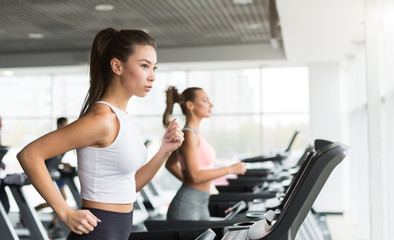 Fototapeta premium Women running on treadmill, doing cardio exercise in gym