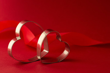 Happy Valentine's Day Greeting card. Two red heart shaped cookie cutters on beautiful red background.
