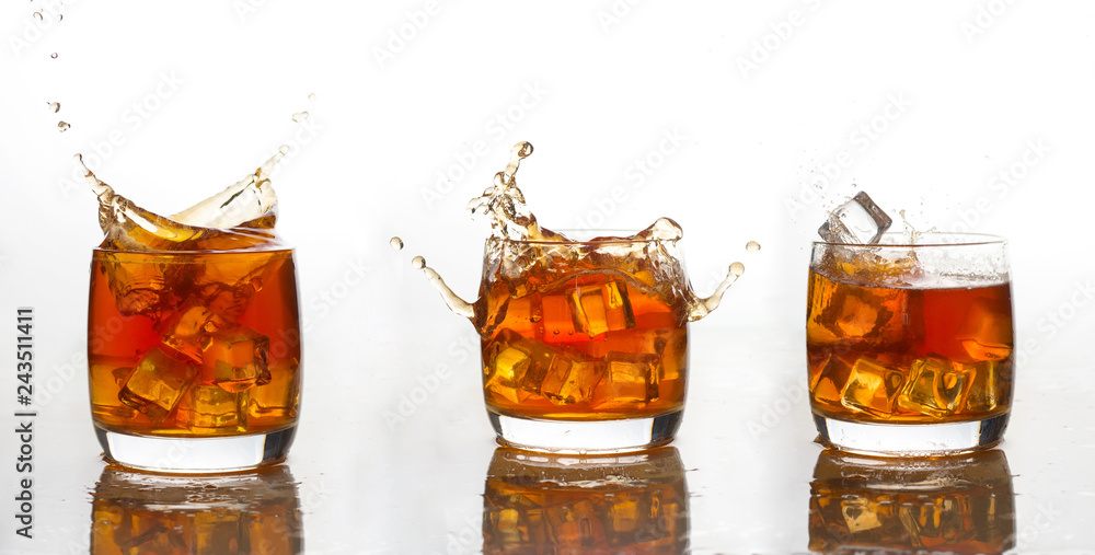 Wall mural whiskey with ice in a glass with splashes